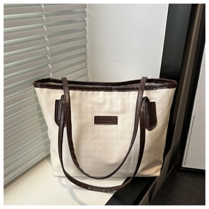Gros plan sur un grand sac cabas bicolore avec texture tissée et écusson logo