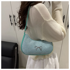 Detail of light blue glitter baguette bag featuring a silver metal bow and slim strap