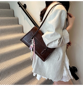 Détail du sac à bandoulière vintage en cuir PU marron foncé avec pompon et boucles en métal