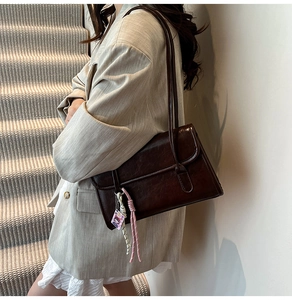 Détail du sac cabas en cuir marron foncé brillant avec bandoulière et pendentif