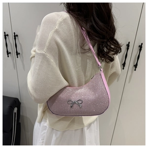 Detail of pink sequin crescent bag with silver bow charm worn over a knit sweater
