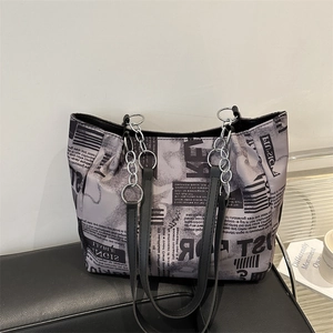 Chic tote bag with newspaper print and chain shoulder strap on black leather bench