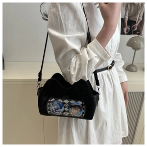 Detail of black cat-ear ita bag showing transparent window with anime badges and strap