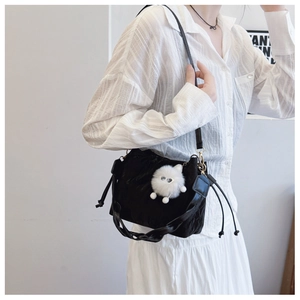 Detail of black velvet drawstring bucket bag with cute white plush doll charm