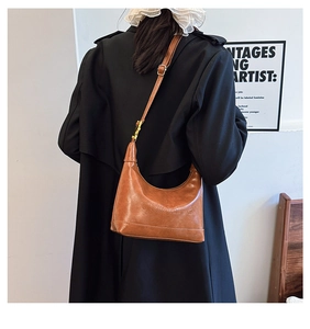 Close-up of caramel brown retro half-moon shoulder bag with embossed brand logo