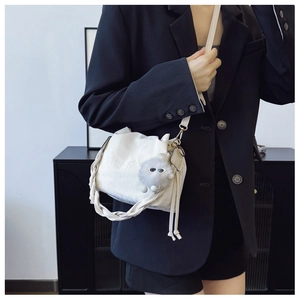 Off-white drawstring bucket bag with woven handle and plush monster charm on model