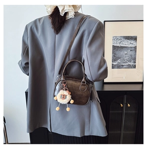 Sac bandoulière marron foncé en forme de coquille avec breloque peluche porté par un mannequin