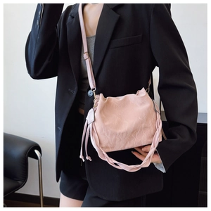 Close-up of pink pleated bucket bag featuring adjustable strap and woven handle detail