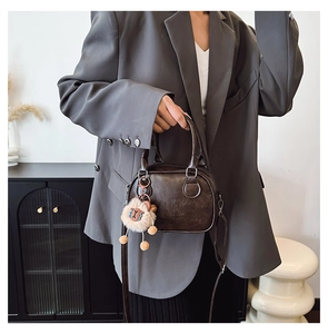 Détail du sac coquille marron foncé avec gaufrage lucky et breloque agneau peluche