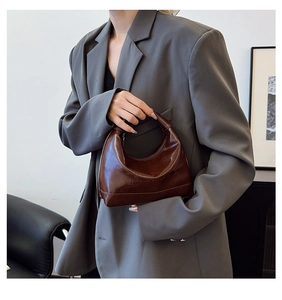 Detailed view of dark brown glossy patent leather bag with embossed letter texture