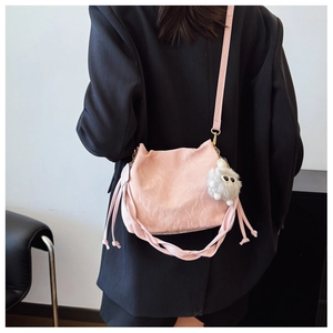 Pink drawstring bucket bag with pleated texture and fuzzy monster charm on a model