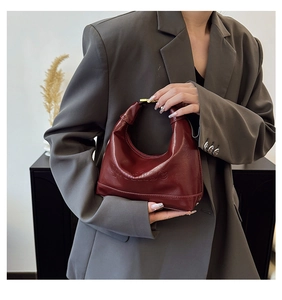 Chic burgundy leather crescent handbag shown with grey blazer in minimalist styling