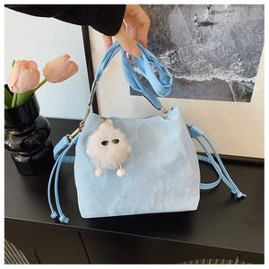 Close-up of light blue drawstring bucket bag with a cute plush monster charm