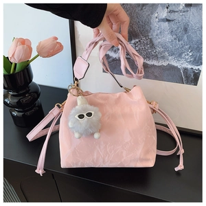 Detail of pink pleated bucket bag texture with cute plush doll and adjustable shoulder strap