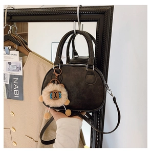 Detail of vintage matte brown bowling bag with a plush lion charm and embossed texture