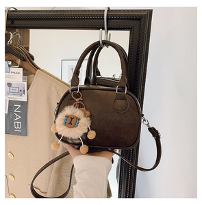 Close-up of retro dark brown bowling bag with a funny plush pendant hanging on a mirror