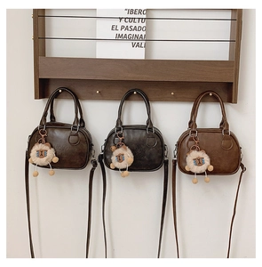 Detailed close-up of retro bowling bags in dark coffee, brown, and black with plush charms