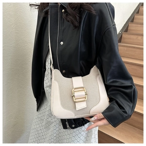Détail du sac crème présentant une texture en mesh et une boucle en métal doré poli