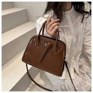 Close-up of retro brown PU leather handbag with cross decorative buckles and handles