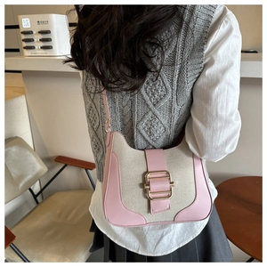 Détail des finitions en cuir rose et texture toile du sac à bandoulière avec boucle dorée