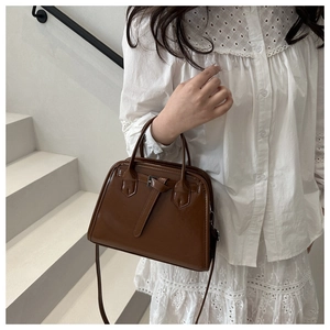 Brown leather tote bag featuring a vintage trapezoid shape and stylish belt buckle detail