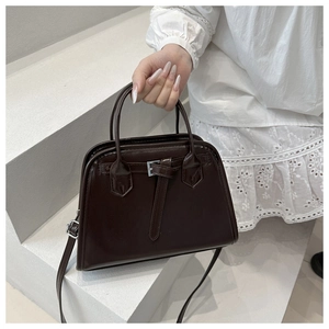Detail of dark brown leather handbag with silver buckle and sleek crossbody strap