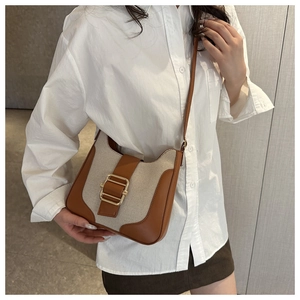 Détail du sac bandoulière rétro en toile et cuir marron avec grande boucle dorée