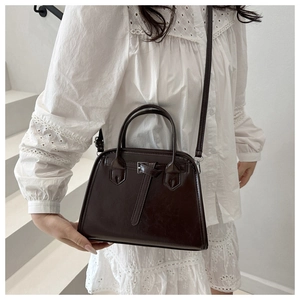 Detail of deep brown vintage square handbag showing glossy leather texture and buckle