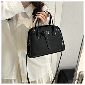 Detail of black faux leather tote with silver metal buckle and decorative cross straps