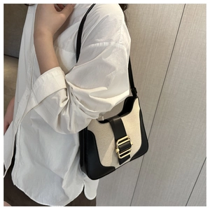 Détail du sac à bandoulière en toile et cuir noir avec un fermoir en métal doré