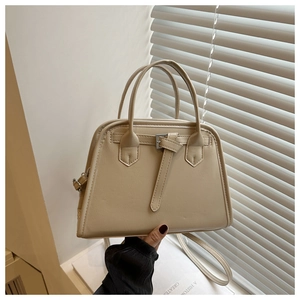 Detail view of beige trapezoid handbag with textured faux leather and adjustable strap