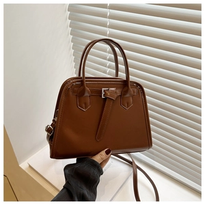 Close-up of a vintage brown leather handbag with decorative buckle and dual handles