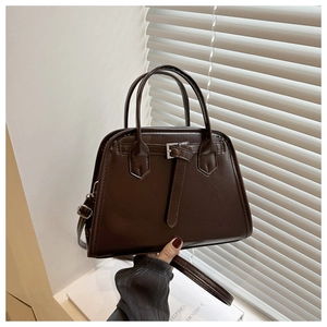 Detail of vintage dark brown glossy leather handbag with top handles and strap