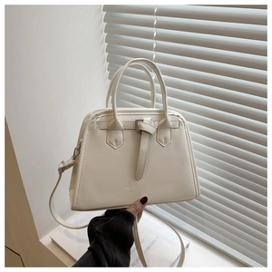 Detail of cream white faux leather trapezoid handbag with buckle and strap in natural light