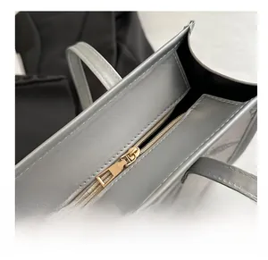 Close-up of smooth gold metal zipper on silver tote bag with textured surface