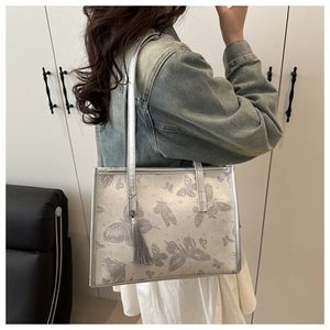 Detail of silver-grey tote bag with butterfly prints and elegant grey silk tassel