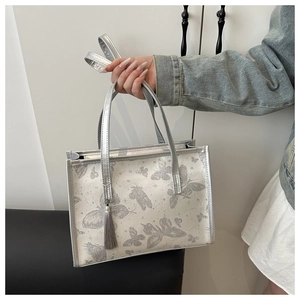 Detail of silver tote bag with butterfly prints, shiny handles and silk tassel charm