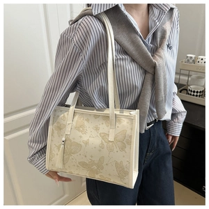 Close-up of vintage summer tote bag featuring gold butterfly print and white tassel charm
