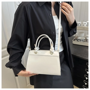 Close-up of white minimalist tote bag with knot handle detail and adjustable shoulder strap