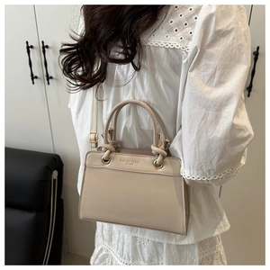 Detail of cream white tote bag with embossed fashion text and gold metal hardware