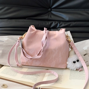 Pink drawstring bucket bag with pleated texture and cute monster charm detail