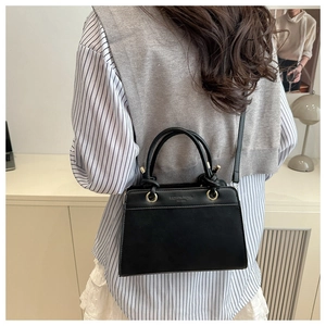 Close-up of black crossbody bag featuring embossed Fashion Trend text and adjustable strap