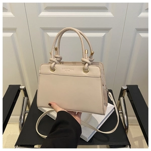 Detail of beige crossbody bag with Fashion Trend embossing and golden hardware