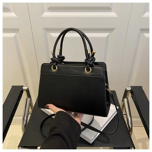 Detail of black PU leather handbag with gold hardware and Fashion Trend embossed text