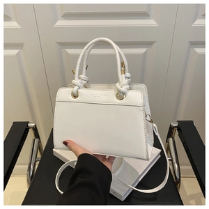 Detail of white leather handbag with knotted rope handle and gold metal ring attachment