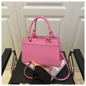 Detail of pink faux leather handbag with knot handle and golden hardware hardware accent