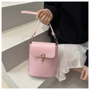 Detail of pink faux leather bucket bag featuring a polished gold metal clasp and adjustable strap
