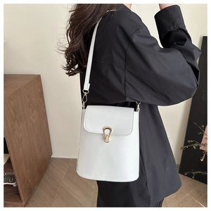 Detail of white leather bucket bag with gold horseshoe buckle on a lifestyle model