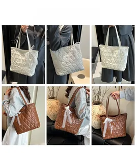 Détail du sac cabas matelassé en blanc et marron avec logo nœud en métal et dentelle