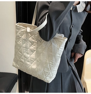 Gros plan du sac cabas matelassé blanc avec bordure en dentelle et nœud en métal